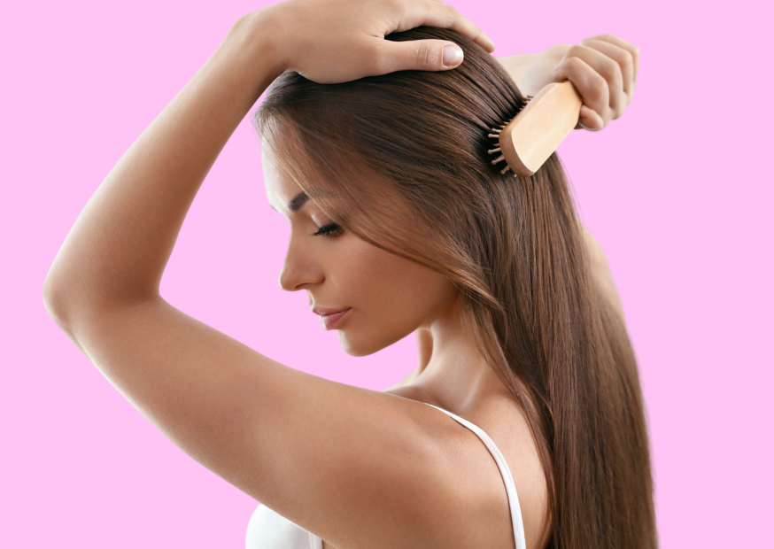 Image of a woman gently brushing her hair with a wide-tooth comb, demonstrating proper techniques to prevent breakage and maintain healthy hair.